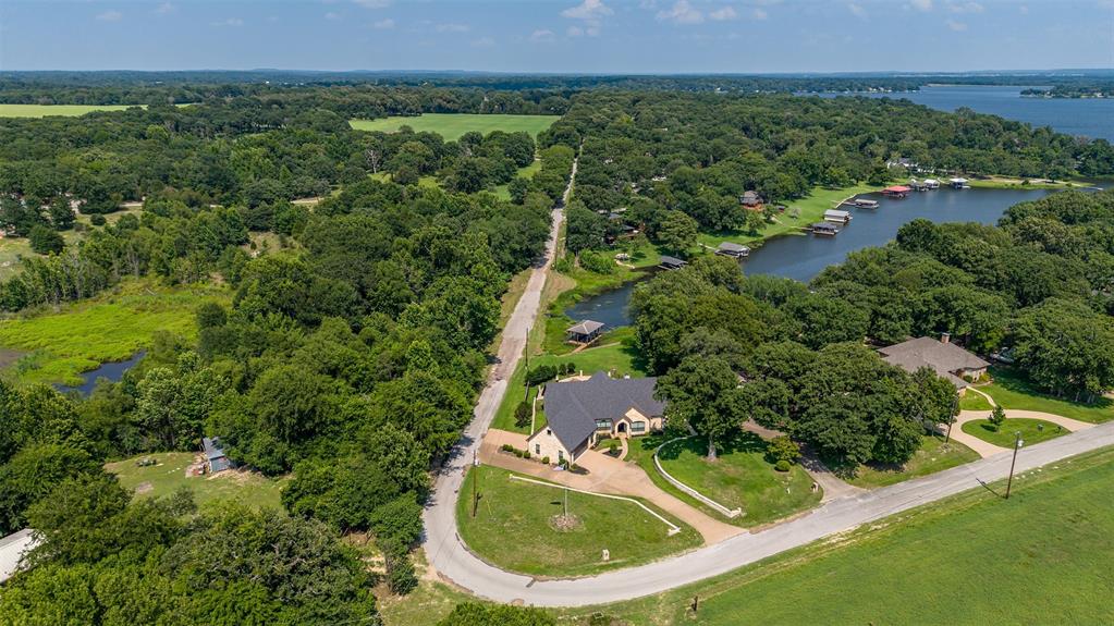 Expansive property featuring a curved driveway, mature trees, and a distant body of water