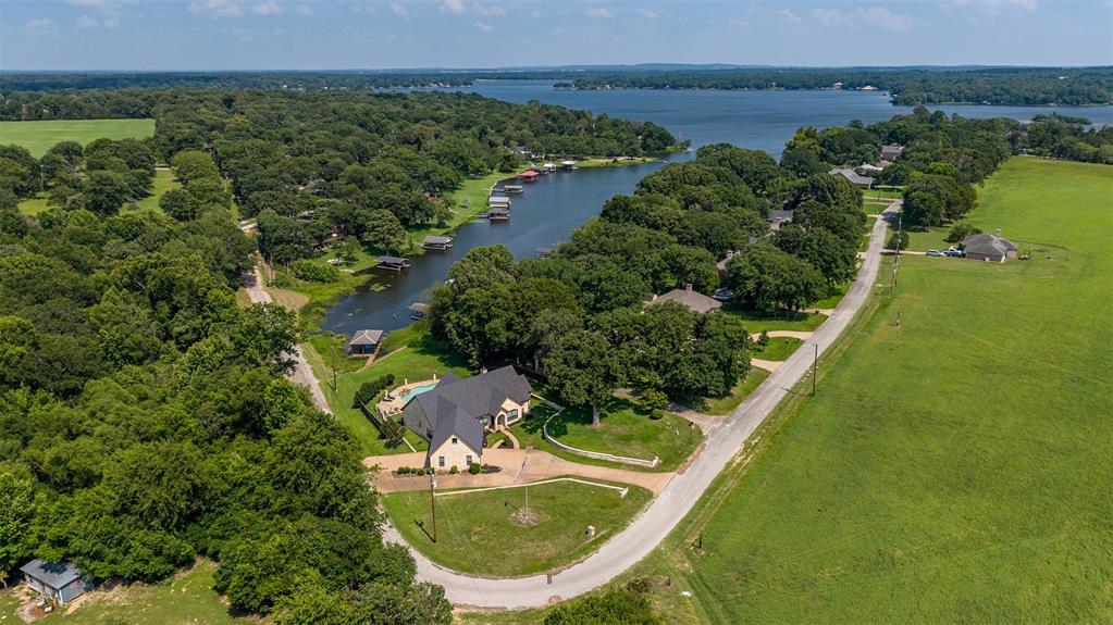 Expansive lakefront property featuring a private boat dock, inground swimming pool, and mature tree coverage