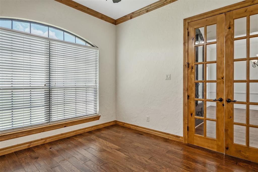 Arch-top window with blinds, wood-finish flooring, and natural wood French doors