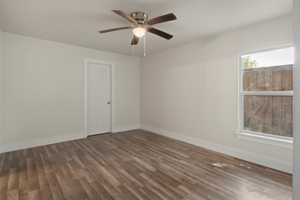 Bright interior room featuring wood-finish flooring, a ceiling fan with integrated lighting, and a white paneled door