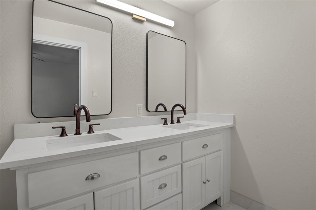 Double vanity featuring white cabinetry, integrated sinks, white countertops, and oil-rubbed bronze hardware