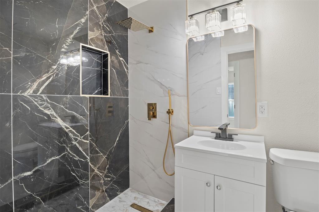 Contemporary bathroom featuring a walk-in shower with dark marbled wall tile and a built-in shower niche