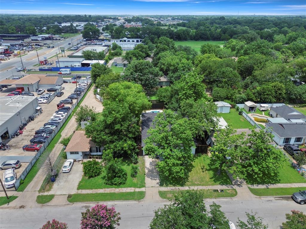 Aerial view of residential properties featuring mature trees, manicured lawns, and a neighborhood with varied structures