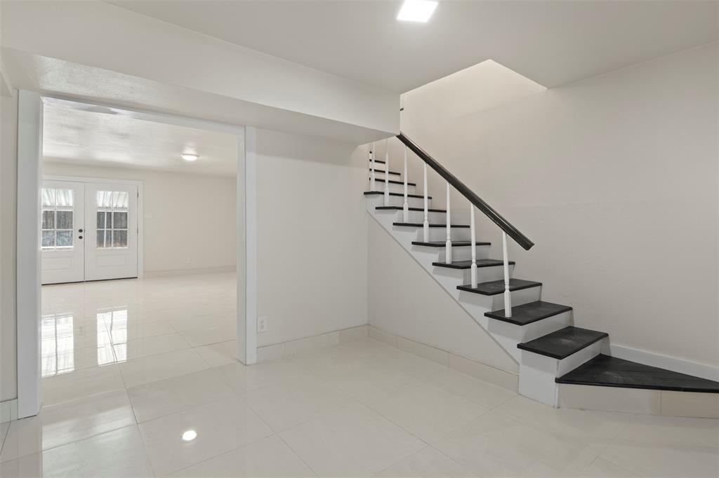 White interior with a prominent staircase featuring a dark handrail and white spindles