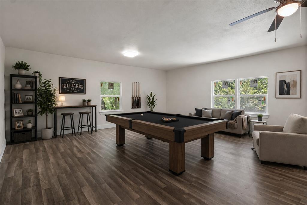 Virtually Staged Spacious room featuring wood-finish flooring, white walls, and multiple windows