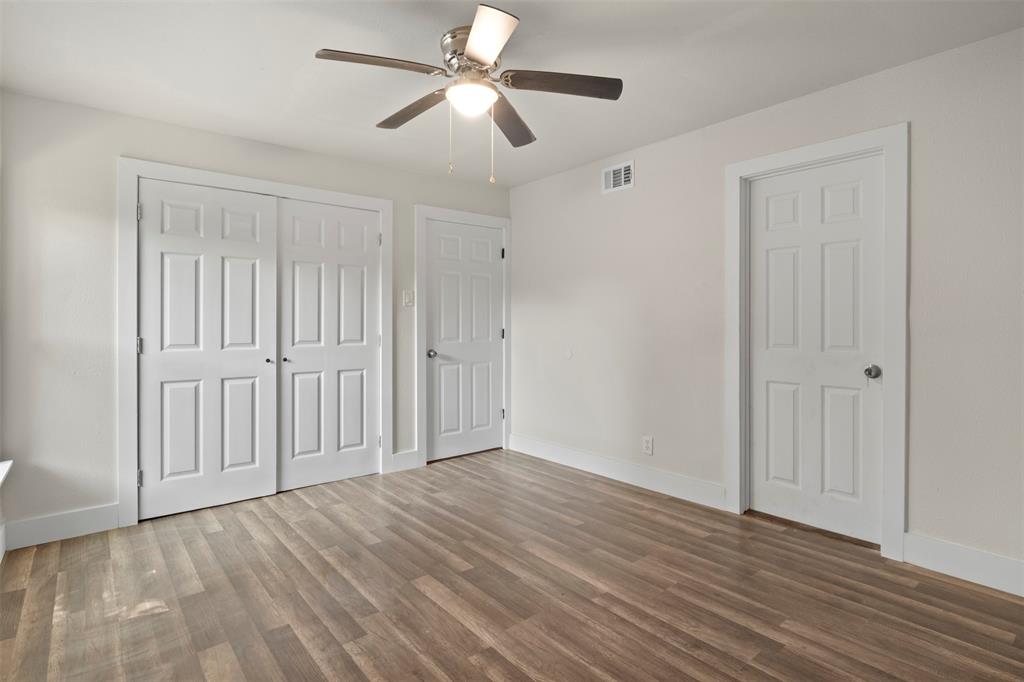 Bright room featuring wood-finish flooring, a ceiling fan with integrated lighting, and white baseboards
