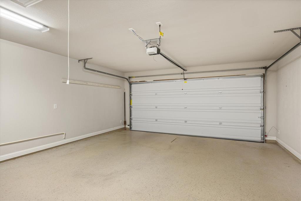 Spacious garage featuring an epoxy coated  floor, overhead lighting, and an automatic garage door opener