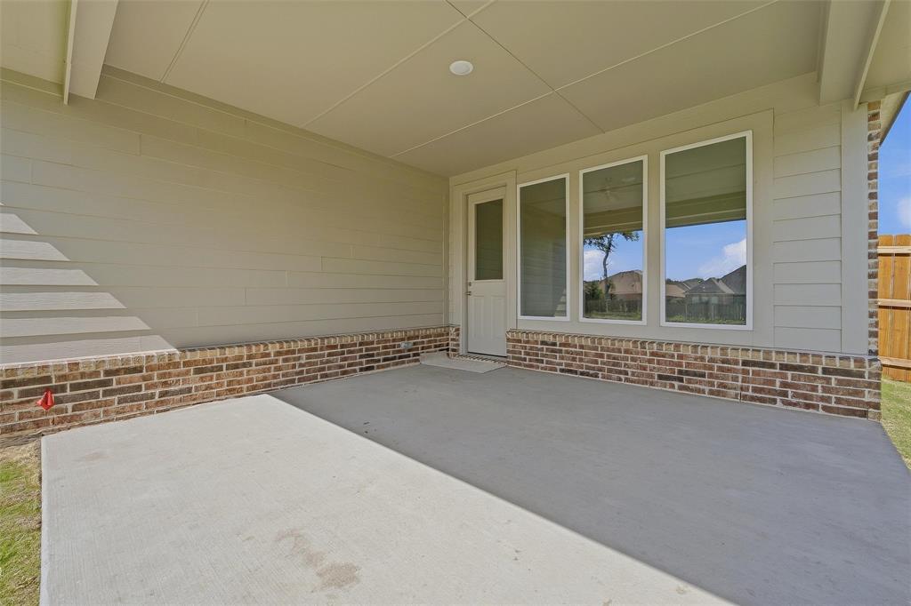 Covered patio with a concrete surface, brick base, and multiple windows