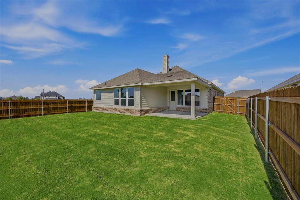Expansive backyard featuring a manicured lawn, full wood fencing, and a covered patio