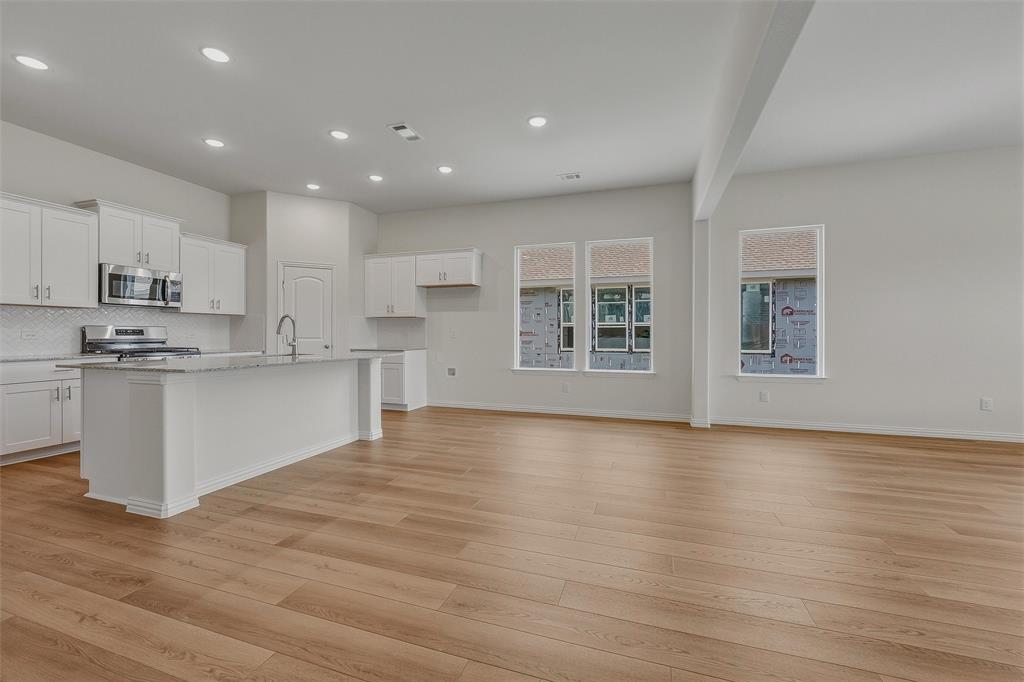 Open-concept living space featuring wood-finish flooring, recessed lighting, and multiple windows