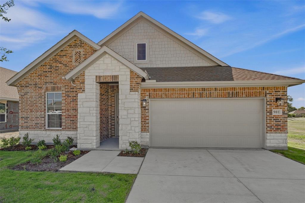 Brick exterior facade with stone accents, covered entry, attached garage, and landscaped front yard