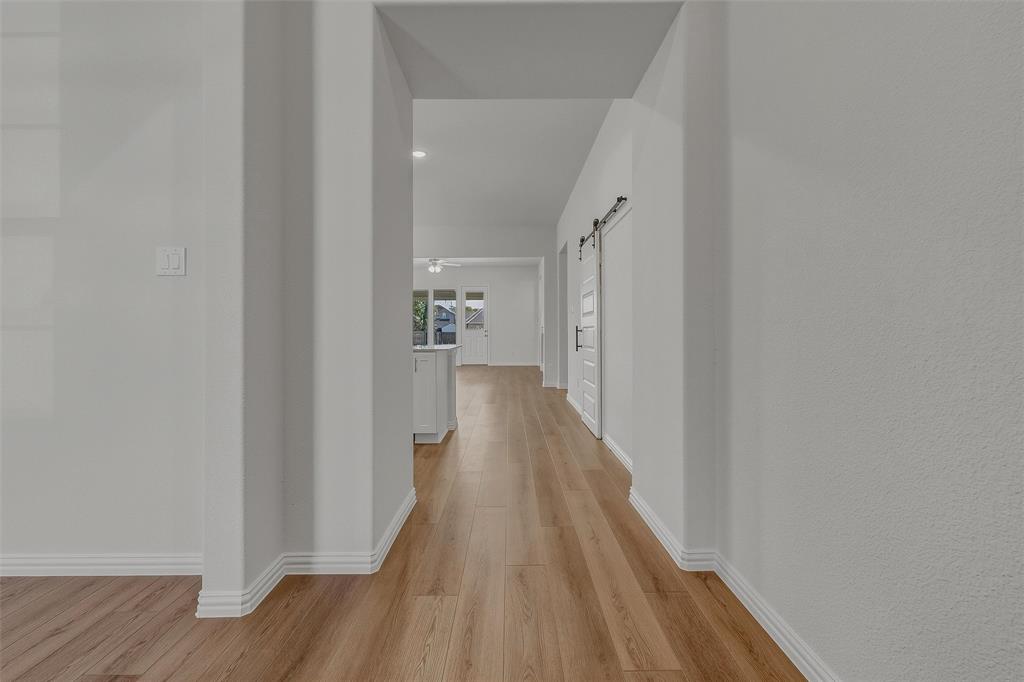 Wood-finish flooring throughout, white interior walls, and a sliding barn door with black hardware