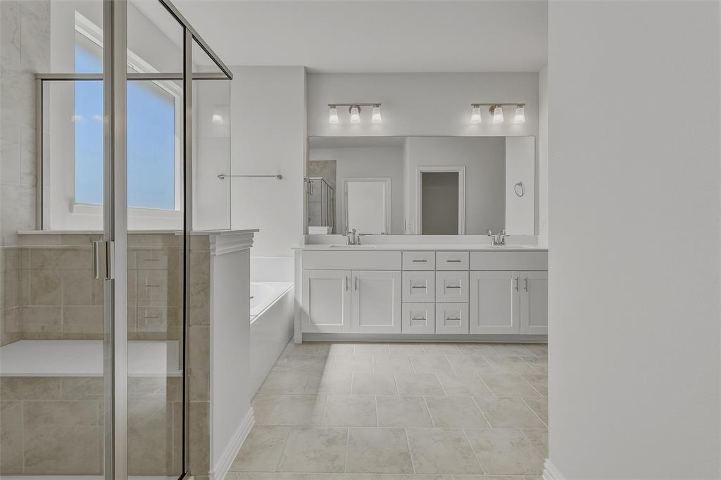 Frameless glass shower enclosure with built-in bench, soaking tub, dual vanity with undermount sinks, and tile flooring