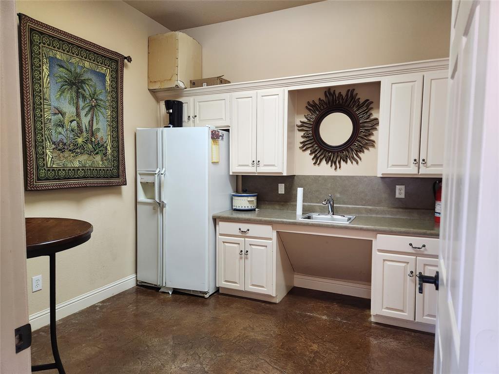 Compact kitchen area featuring white cabinetry, a stainless steel sink, and durable concrete-finish flooring
