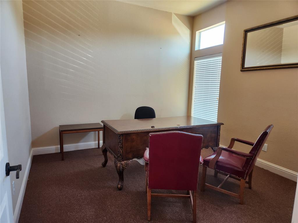 Carpeted room featuring a decorative wood desk, crown molding, and a transom window