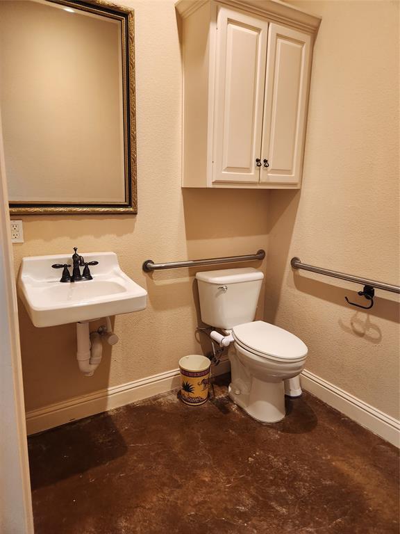 Bathroom featuring a wall-mounted sink with black fixtures, a white toilet, and a framed mirror