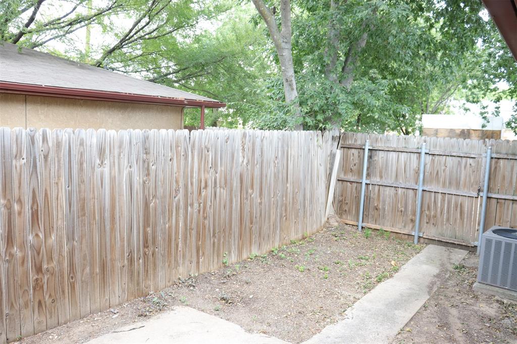 Private outdoor space featuring a wood fence, concrete patio, and mature trees