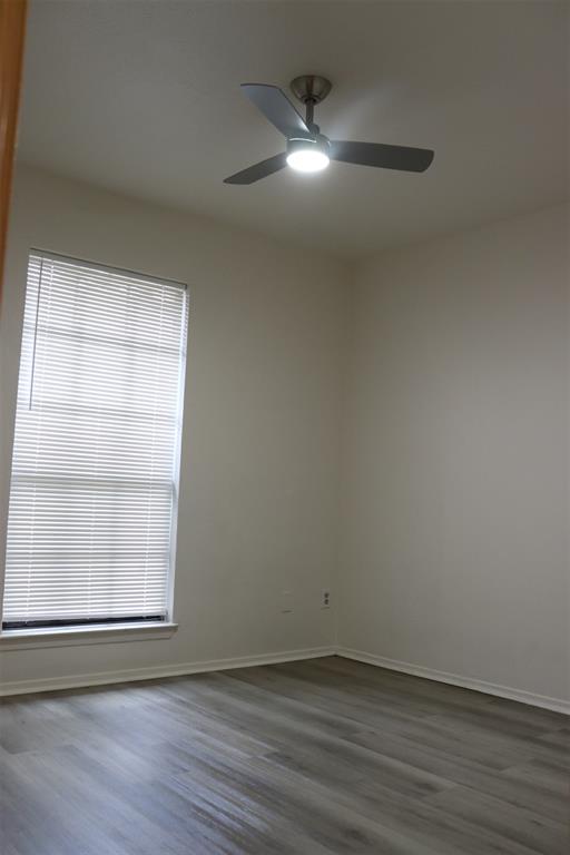 Interior room featuring light gray wood-finish flooring, a window with horizontal blinds, and a ceiling fan with integrated lighting