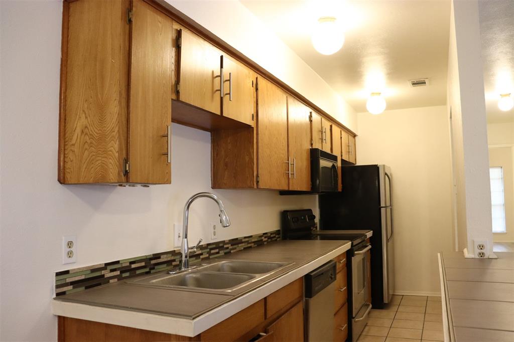 Kitchen featuring wood cabinetry, dual basin stainless steel sink with a gooseneck faucet, mosaic tile backsplash, and tile flooring