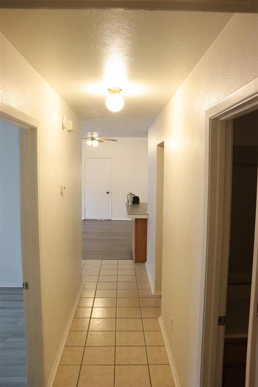 Hallway featuring tile flooring, neutral wall tones, and recessed lighting leading to an open living area with wood-finish flooring and a ceiling fan
