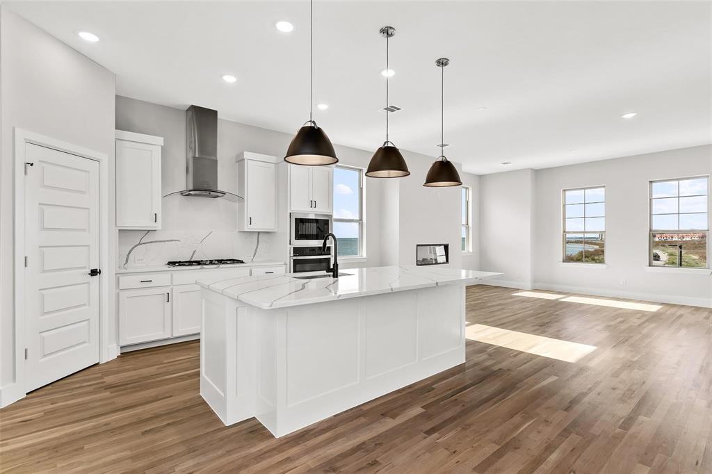 White quartz countertops, oversized breakfast bar island, gas cooktop, double ovens, walk in pantry