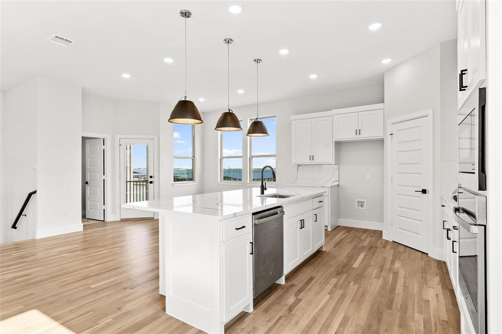 Oversized kitchen island with pendant lighting open to living area perfect for entertaining. Stainless appliances with gas cooktop