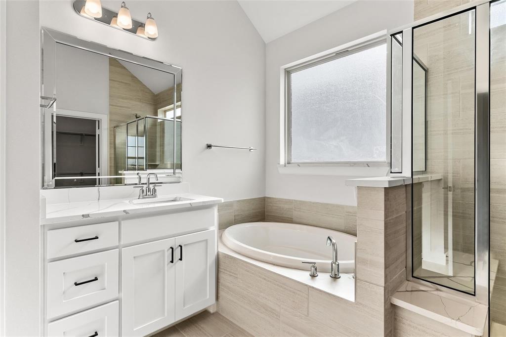 Primary bathroom with dual vanities, separate tub and walk in shower.