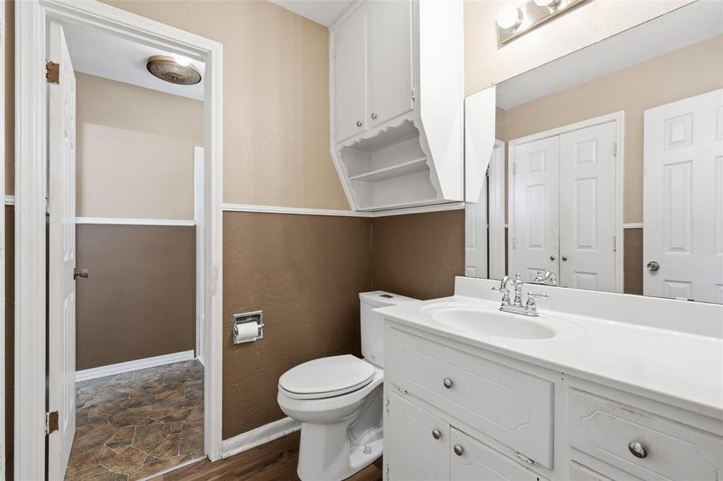 Bathroom featuring a single vanity with an integrated sink, chrome faucet, and a large wall-mounted mirror