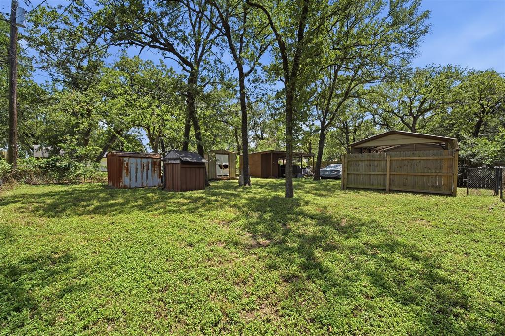 Expansive green space featuring mature trees and multiple storage structures