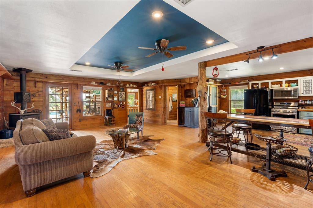Open-concept living space featuring wood-finish flooring, wood plank walls, and a blue tray ceiling with recessed lighting