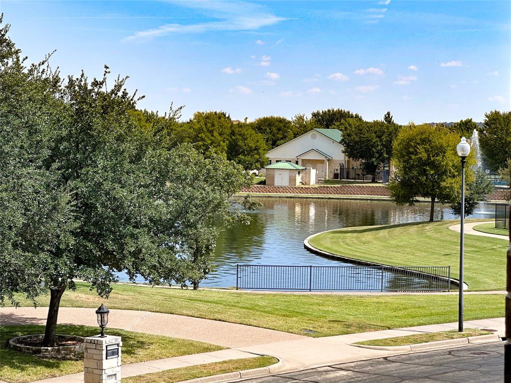 Waterfront property featuring a curved shoreline, manicured green space, and mature trees