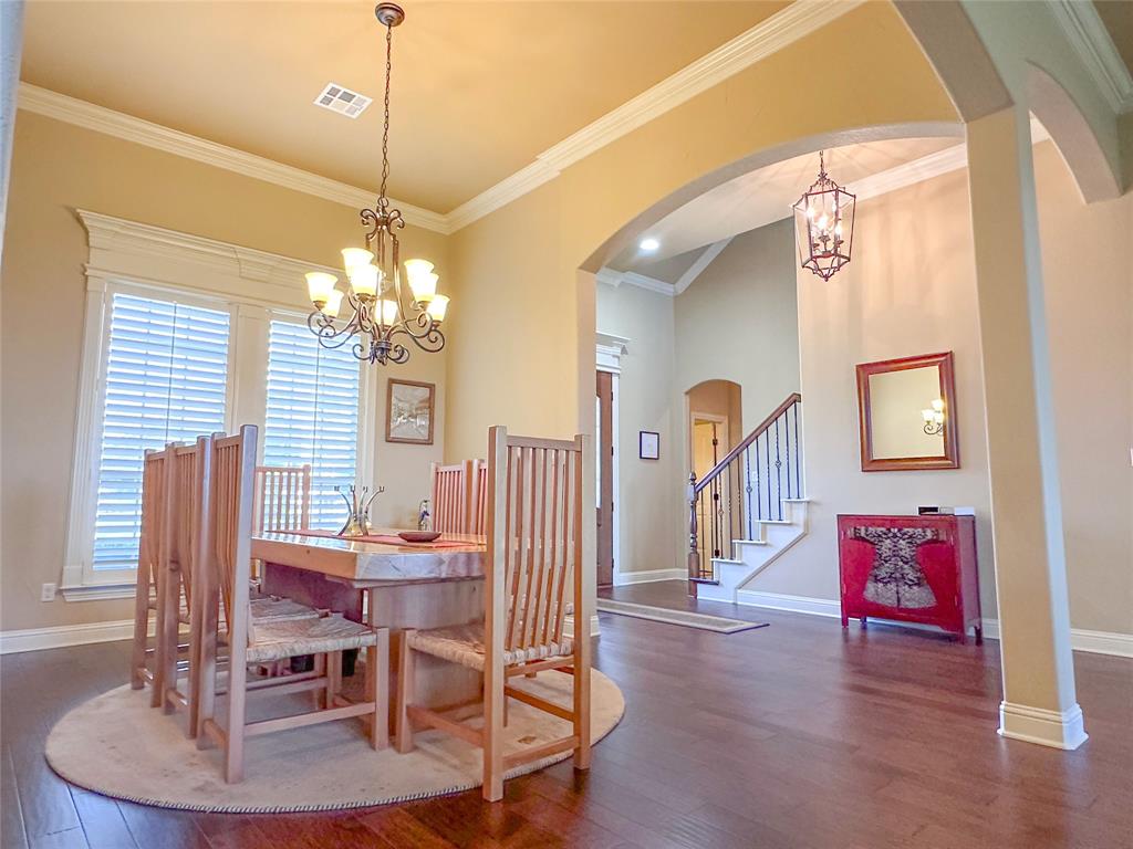 Formal dining area featuring rich wood-finish flooring, crown molding, and a chandelier