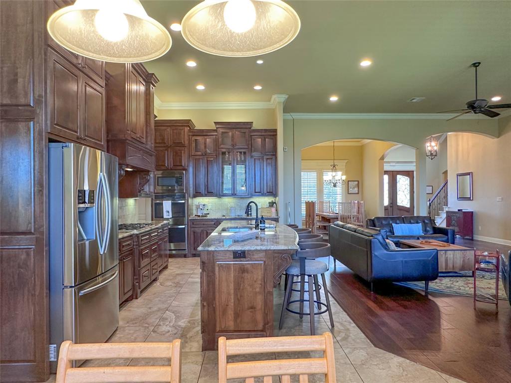 Kitchen featuring dark wood cabinetry, stainless steel appliances, a center island with a granite countertop, and recessed lighting
