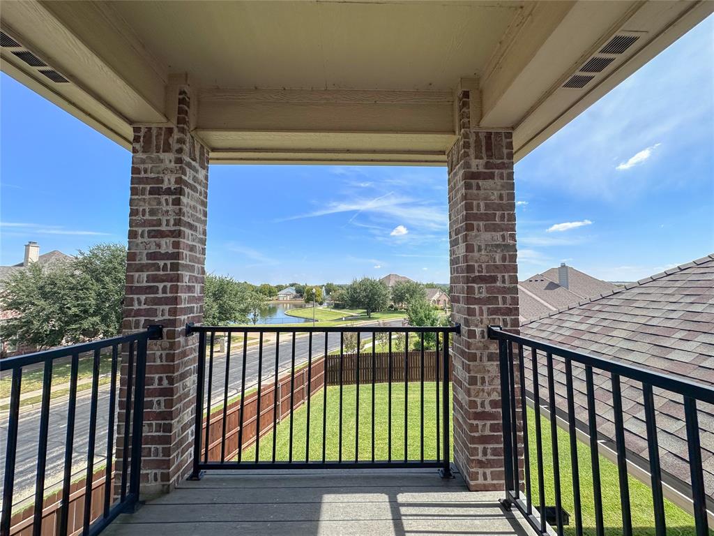 Second-story balcony featuring brick columns, black metal railing, and composite decking