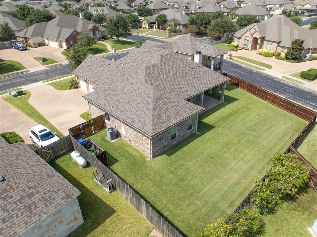 Expansive backyard featuring a manicured lawn, full perimeter privacy fencing, and a covered patio area