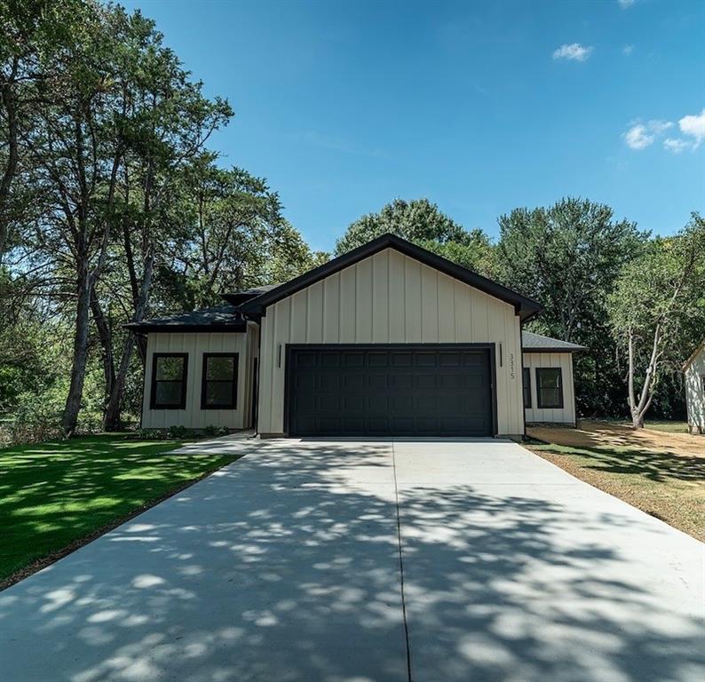 Modern farmhouse-style exterior featuring vertical panel siding, a dark-toned garage door, and a black-trimmed roofline