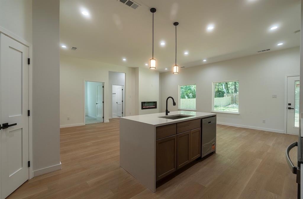 Kitchen island with a built-in sink and dishwasher, featuring pendant lighting and recessed lighting throughout