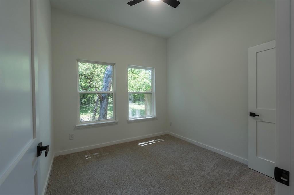 Interior room featuring two windows, neutral carpeting, and a ceiling fan