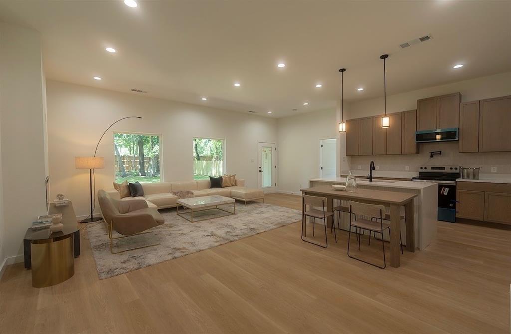 Open-concept living space featuring wood-finish flooring, recessed lighting, and large windows