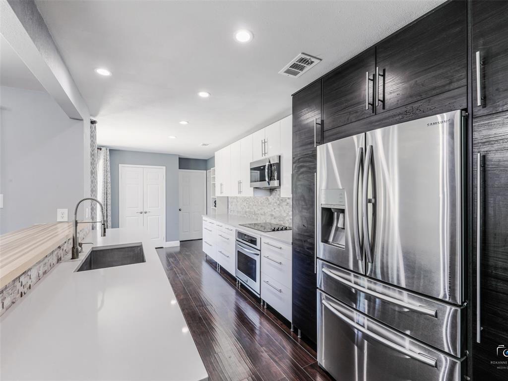 Modern updated kitchen featuring dark wood-finish flooring, quartz-style counters, stone backsplash and recessed lighting.  Fridge to convey with the property.