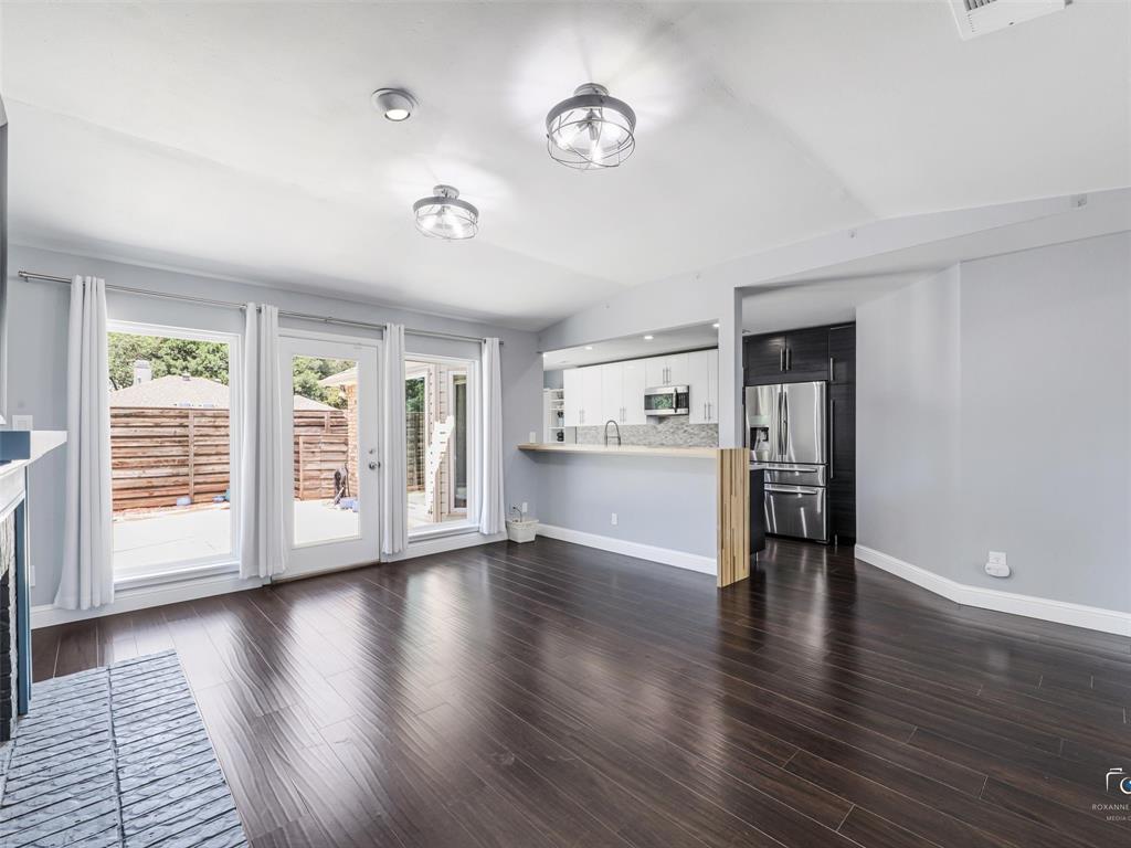 Open-concept living area featuring dark wood-finish flooring opens to the updated kitchen. Note that board on board fence in the backyard!