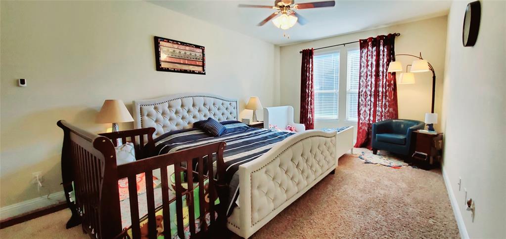 Spacious room featuring carpeting, a ceiling fan with light fixture, and windows with blinds