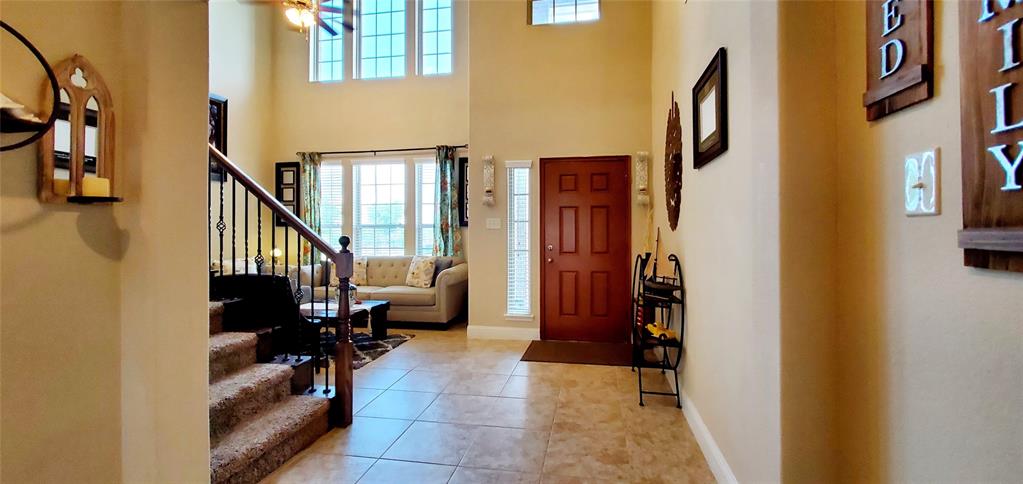 Two-story foyer featuring tile flooring, a dark wood entry door with a sidelight, and a staircase with dark wood newel posts and wrought iron balusters