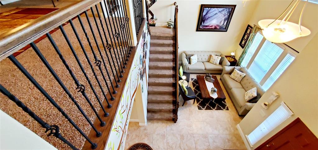 Grand entry featuring a two-story ceiling, a staircase with decorative wrought iron balusters and a wood handrail, and high-set windows