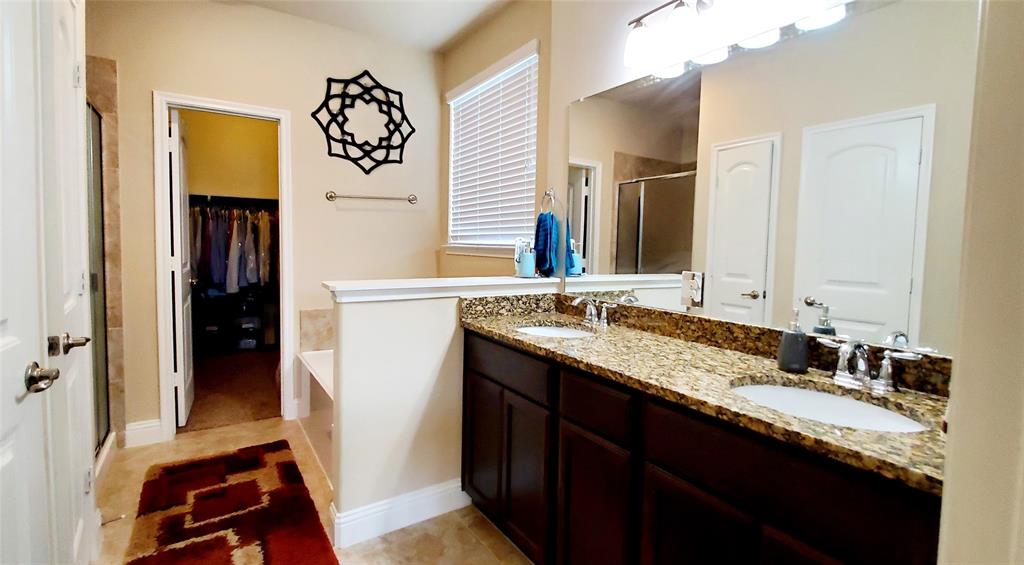 Bathroom with a dual vanity featuring a granite countertop and dark wood cabinetry