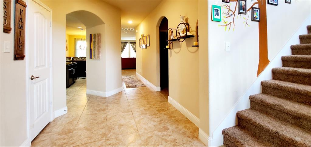 Entryway featuring tile flooring, archways, a white paneled door, and a carpeted staircase