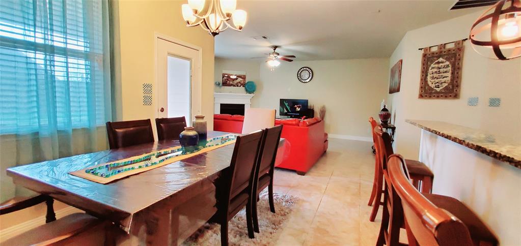 Dining area with a multi-light chandelier, featuring a wood-finish dining table and direct access to another room