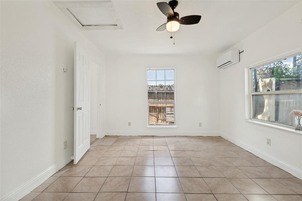 Bright room featuring neutral tile flooring, white walls, two windows, and a ceiling fan with integrated lighting