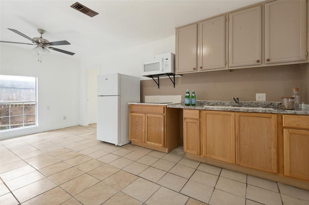 Kitchenette with tile flooring, light wood-finish base cabinetry, and contrasting upper cabinetry