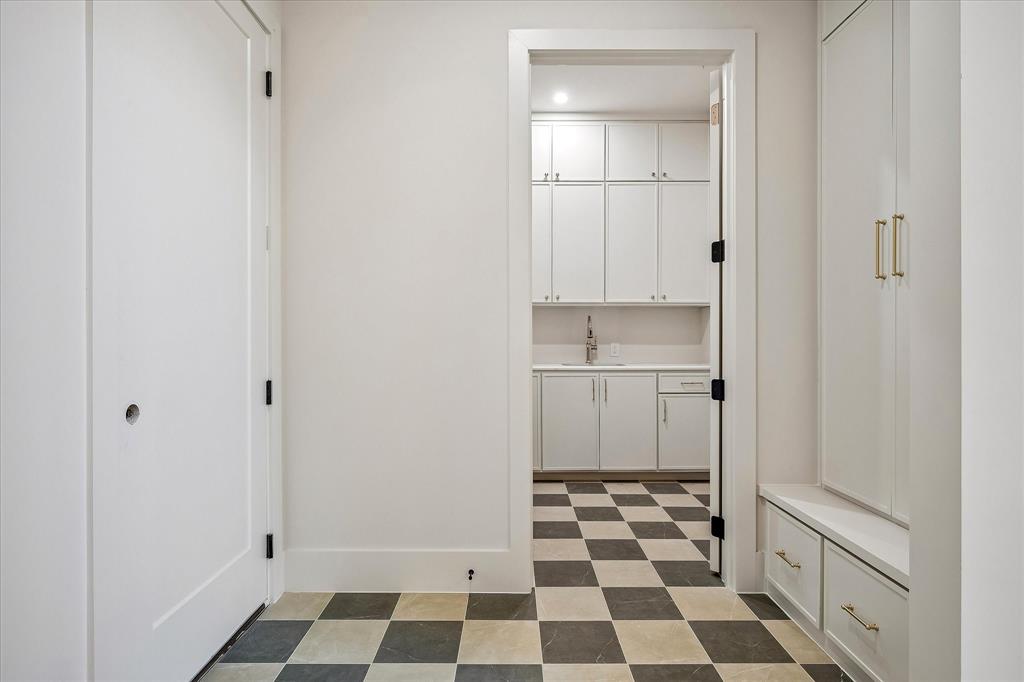 Mud room, checkered tile floor, built-in cabinetry, access to laundry